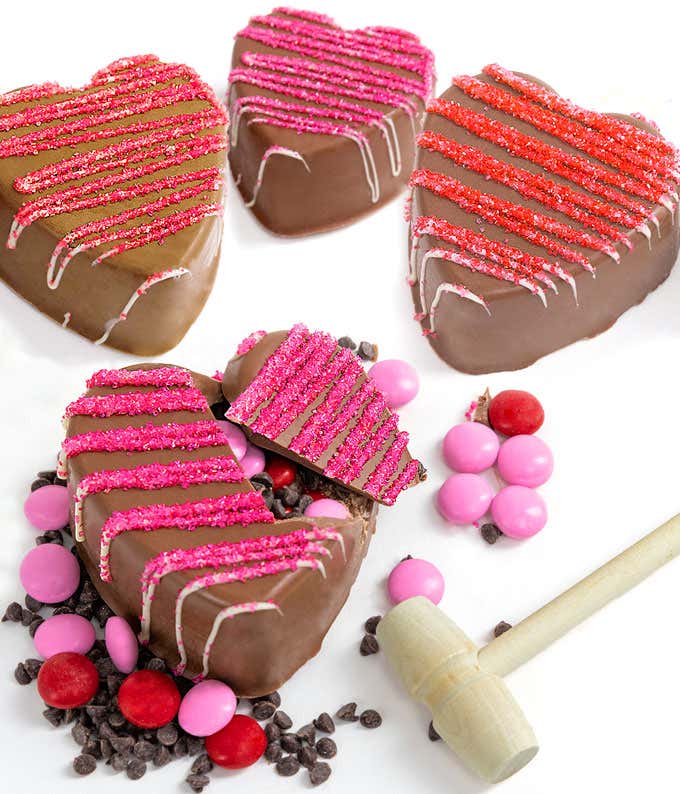 Four heart shaped breakable chocolates, filled with pink and red M&M's, and miniature chocolate chips.