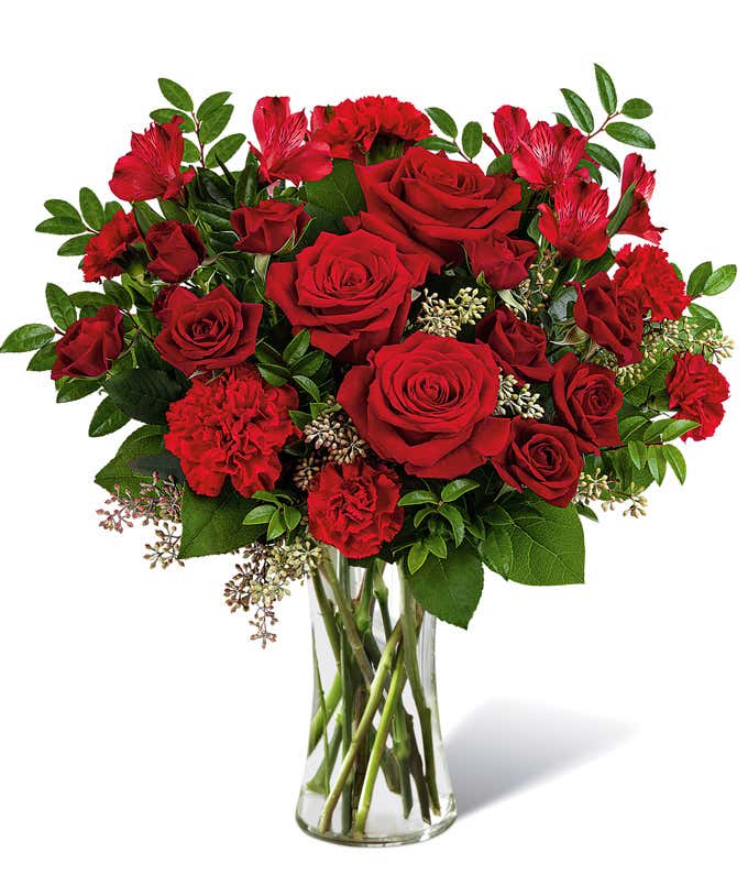 Full arrangement of red roses and carnations in a tall red mosaic vase,