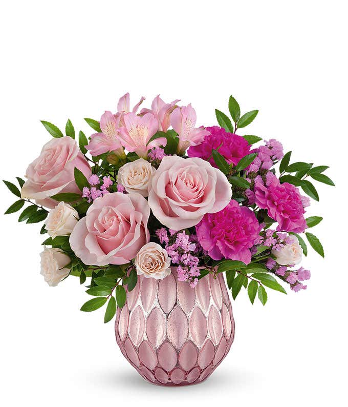 A bouquet of pink roses, light pink spray roses, pink alstroemeria, & fuchsia carnations in a metallic pink vase with geometric textures