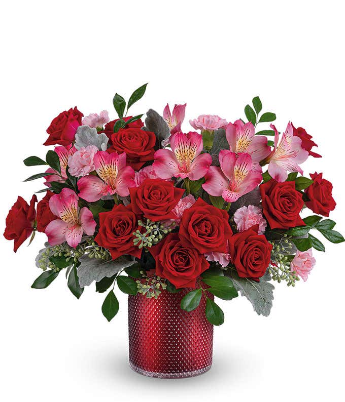 A bouquet of red roses, pink roses, red spray roses, pink alstroemeria with floral greens in a red shimmery studded cylinder vase (Pink roses available in Premium size only)