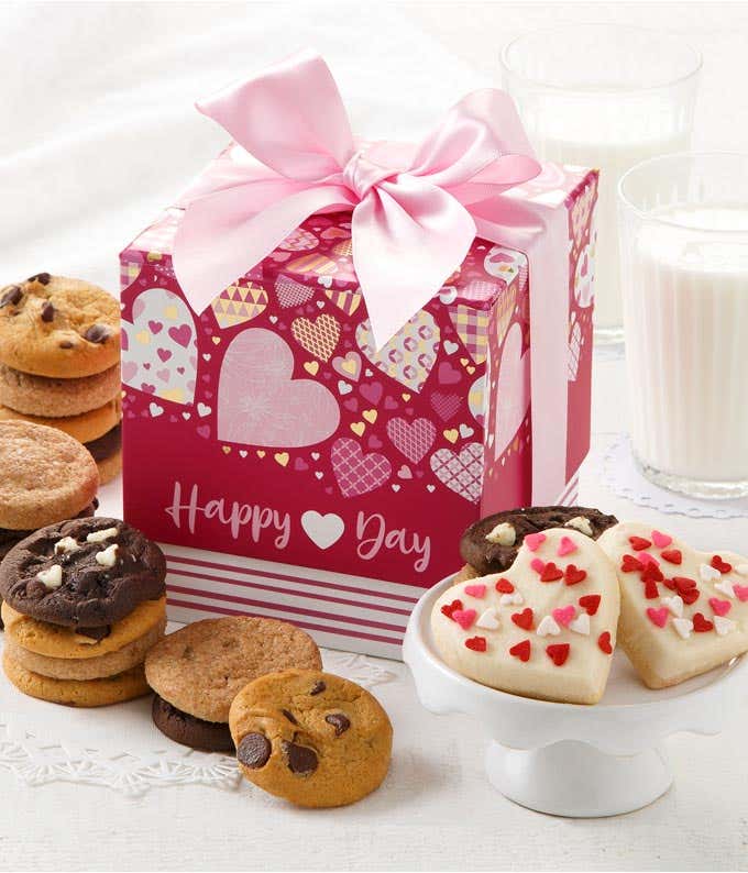 A pink gift box with hearts and a pink bow with an assortment of cookies in front with frosted heart cookies